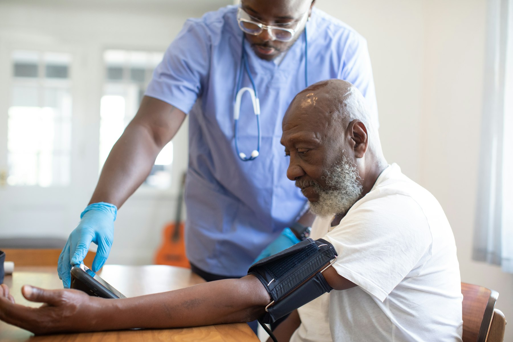 A nurse taking a patient's blood pressure during a home visit